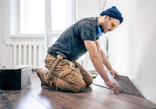 Building contractor worker using hand held worm drive circular saw to cut boards on a new home constructiion project.